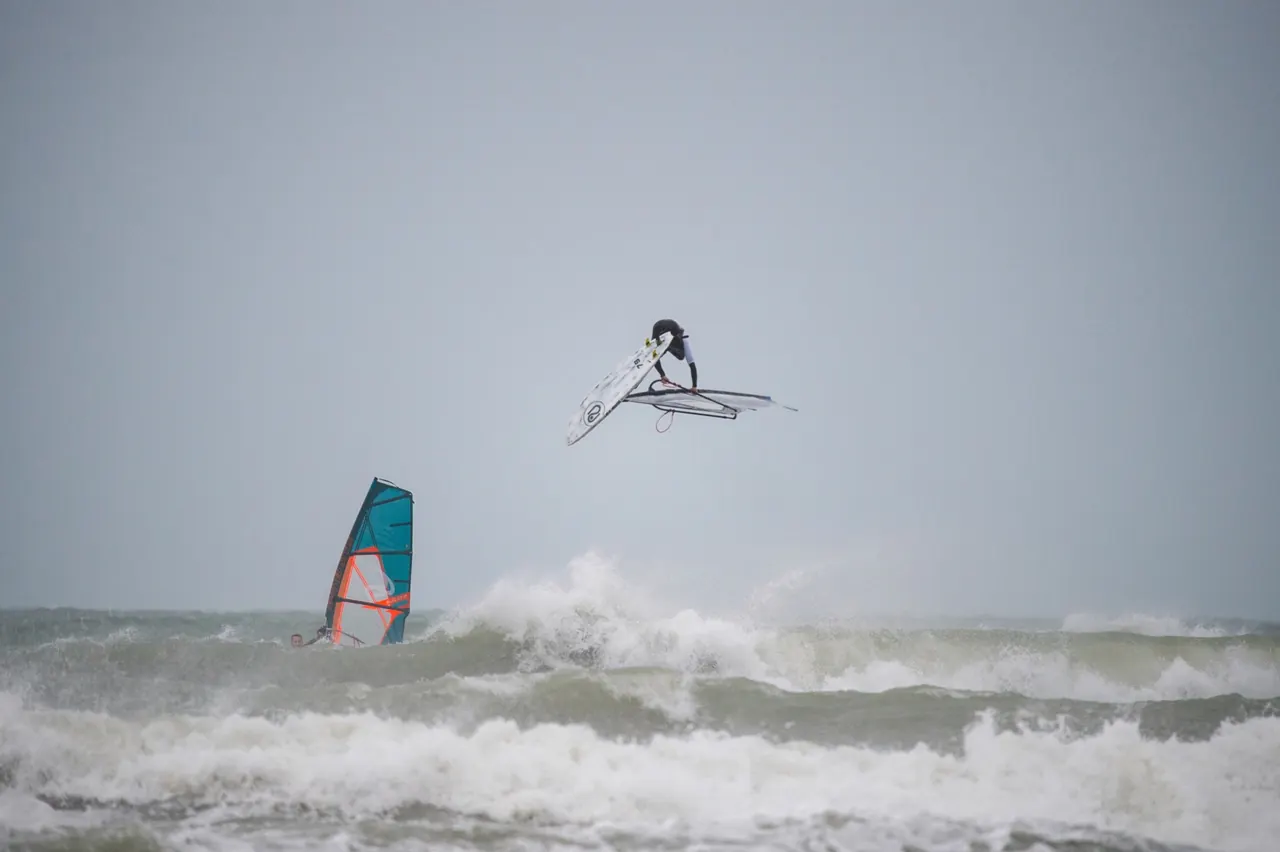 Windsurfer hoog in de lucht boven de golven