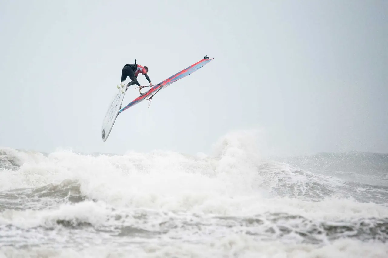 Windsurfer in de lucht boven brekende golven