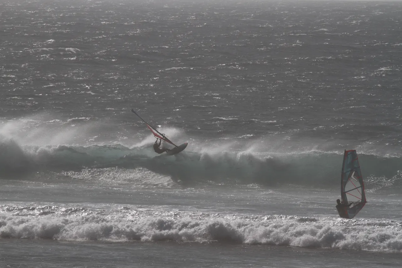 Windsurfer op de golven bij grijze lucht