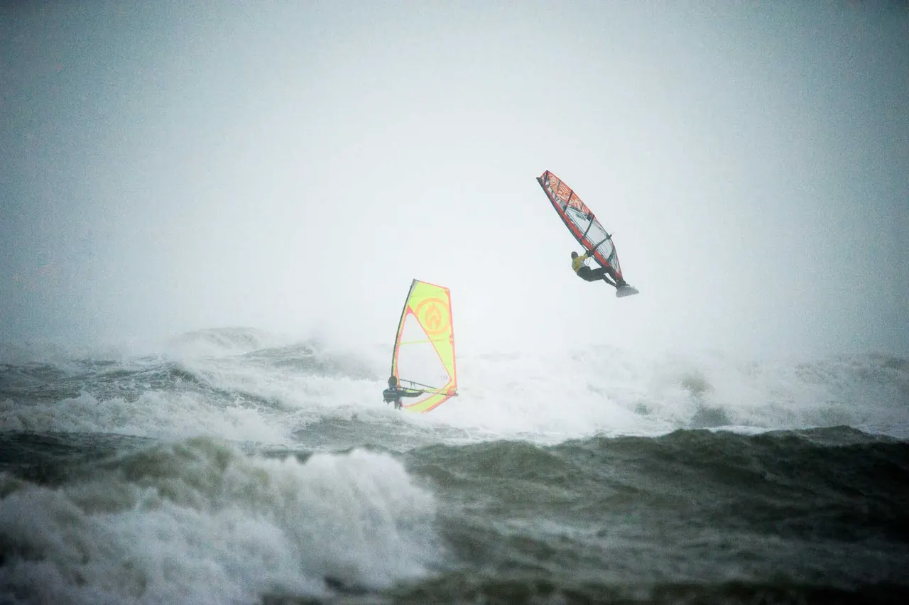 Windsurfers in de regen en wilde branding van Wimereux