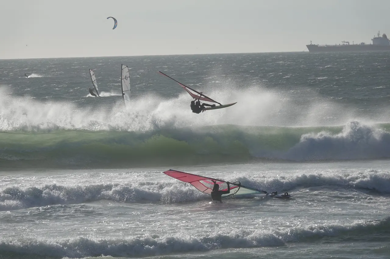 Windsurfers tussen de golven bij de havendam
