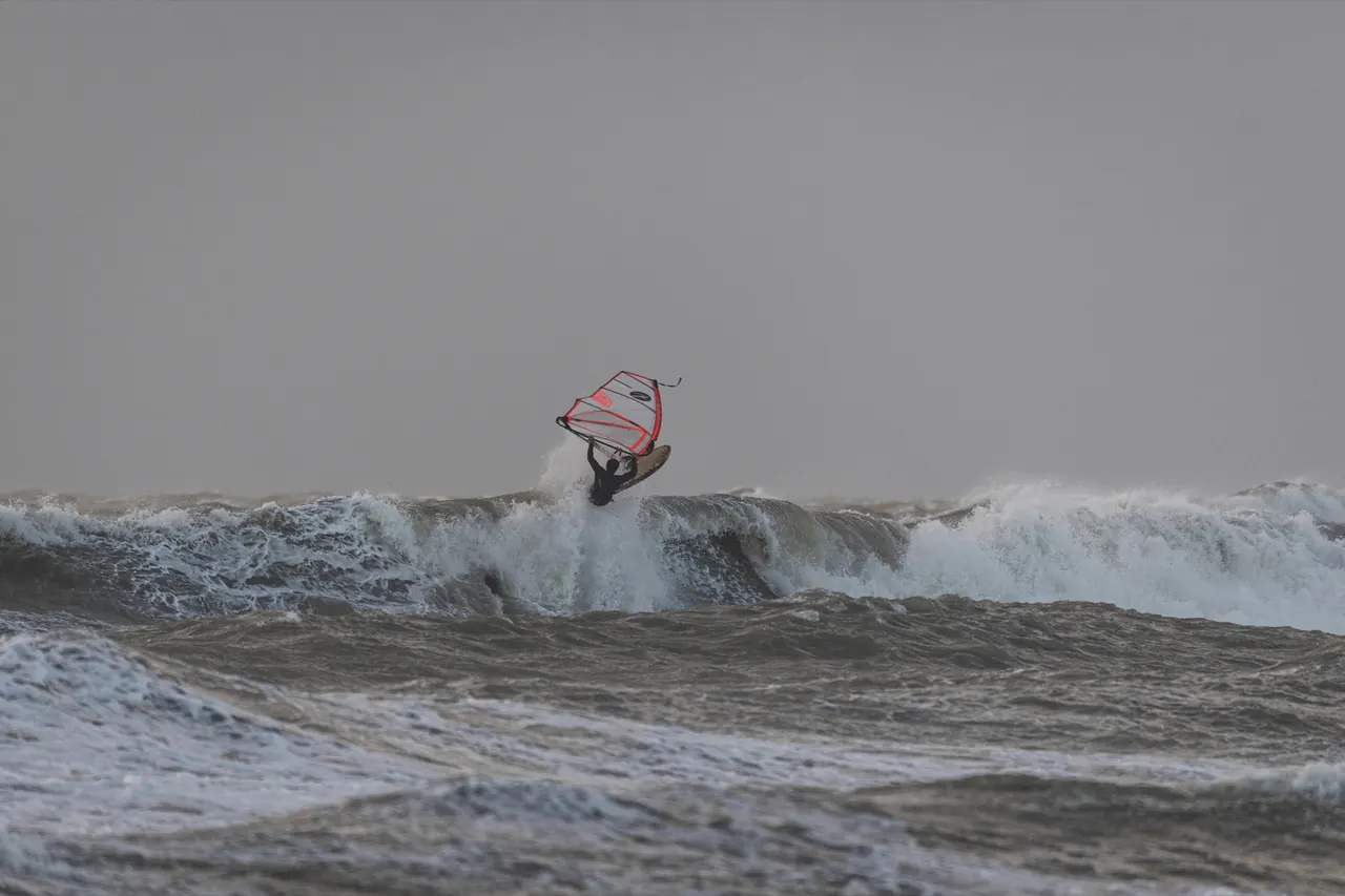 Sprong met rood zeil boven een golf